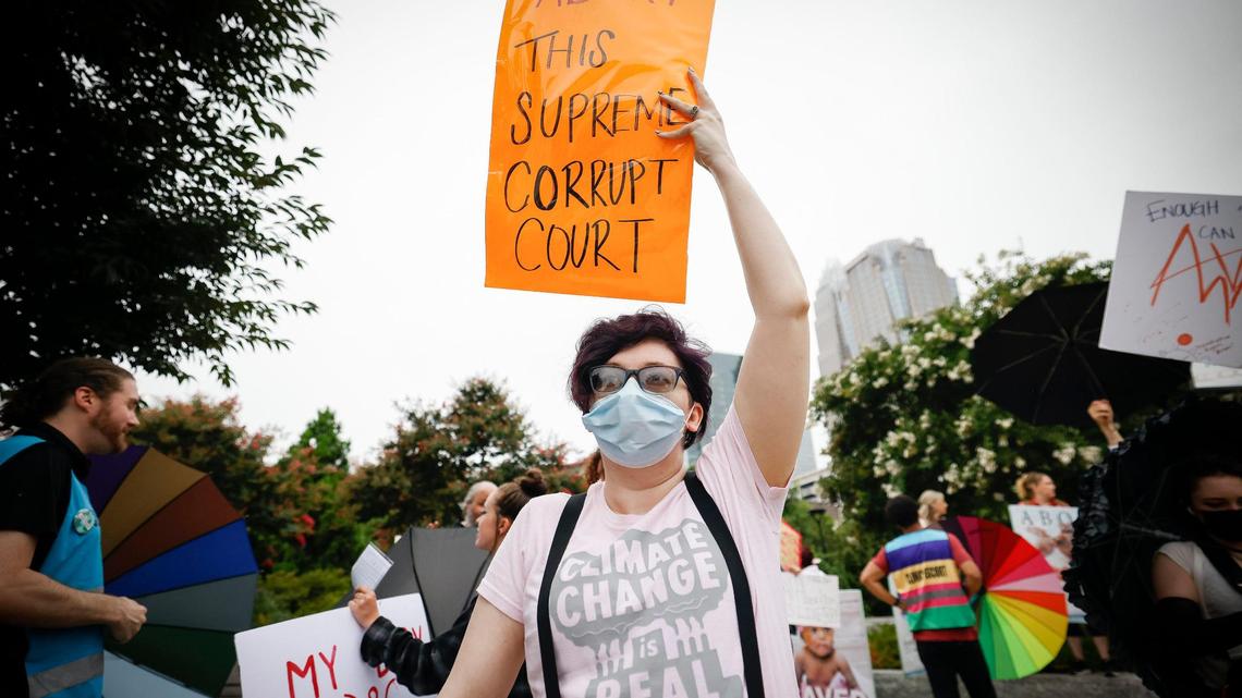 Abortion rights activist Jennifer Williams, of Charlotte, holds a sign along side other demonstrators during a rally at First Ward Park in Charlotte on Sunday night.