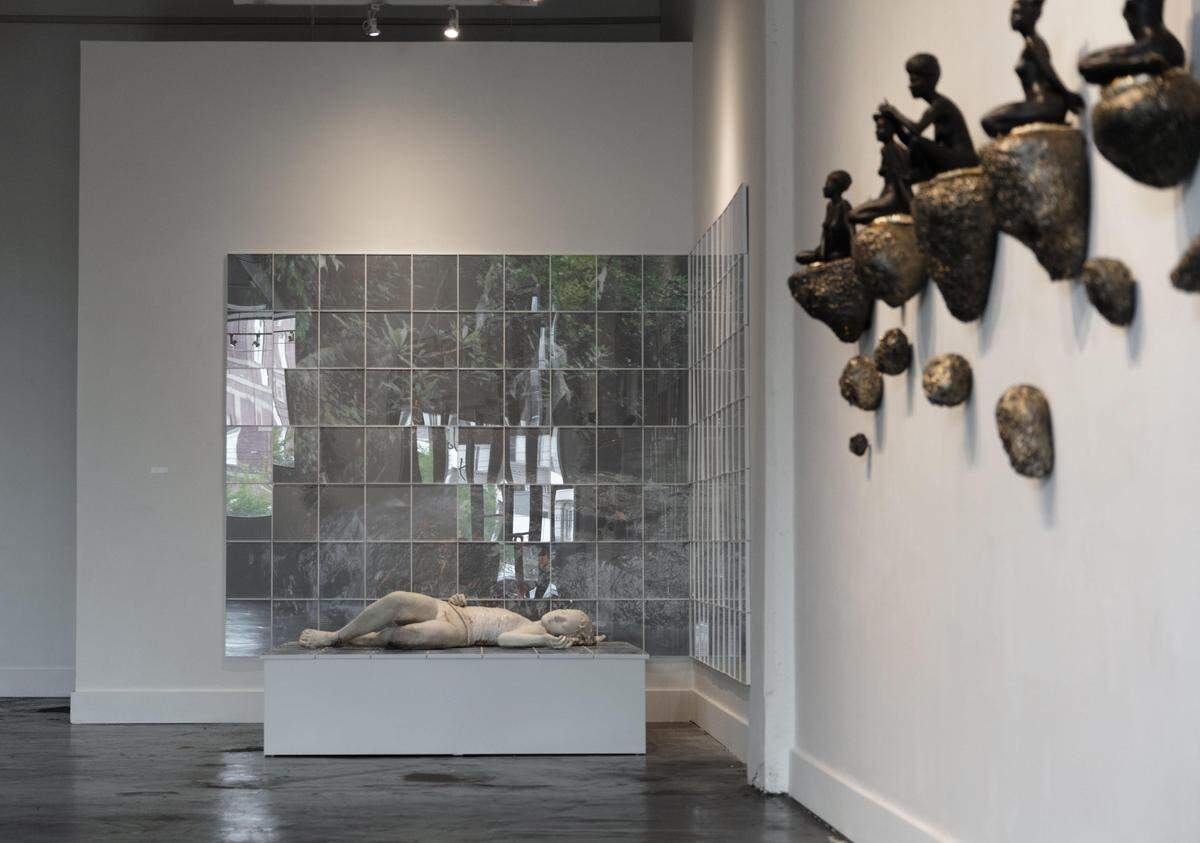 Works on view in Cristina Córdova’s “Cuerpo Exquisito” exhibition include stylistically consistent figures in varying scales, postures and ceramic finishes. On the right in this photo are five small feminine figures that rest atop a wall of mounted ceramic rocks.