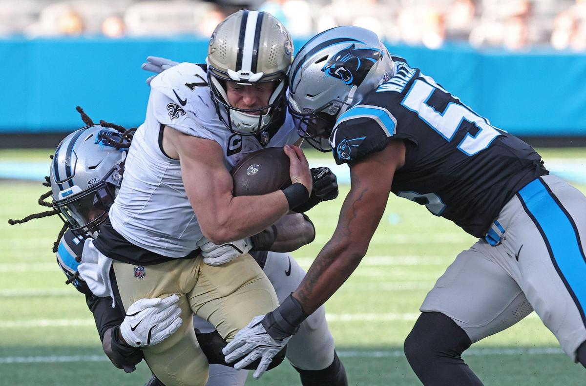 Carolina Panthers linebacker Jadeveon Clowney, left, and linebacker Trevin Wallace, right, make the tackle on New Orleans Saints tight end Taysom Hill, center, during second-half action at Bank of America Stadium in Charlotte, NC on Sunday, November 3, 2024. The Panthers defeated the Saints 23-22.