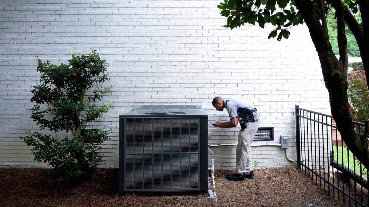 A home inspector checks an HVAC unit outside a home in south Charlotte.