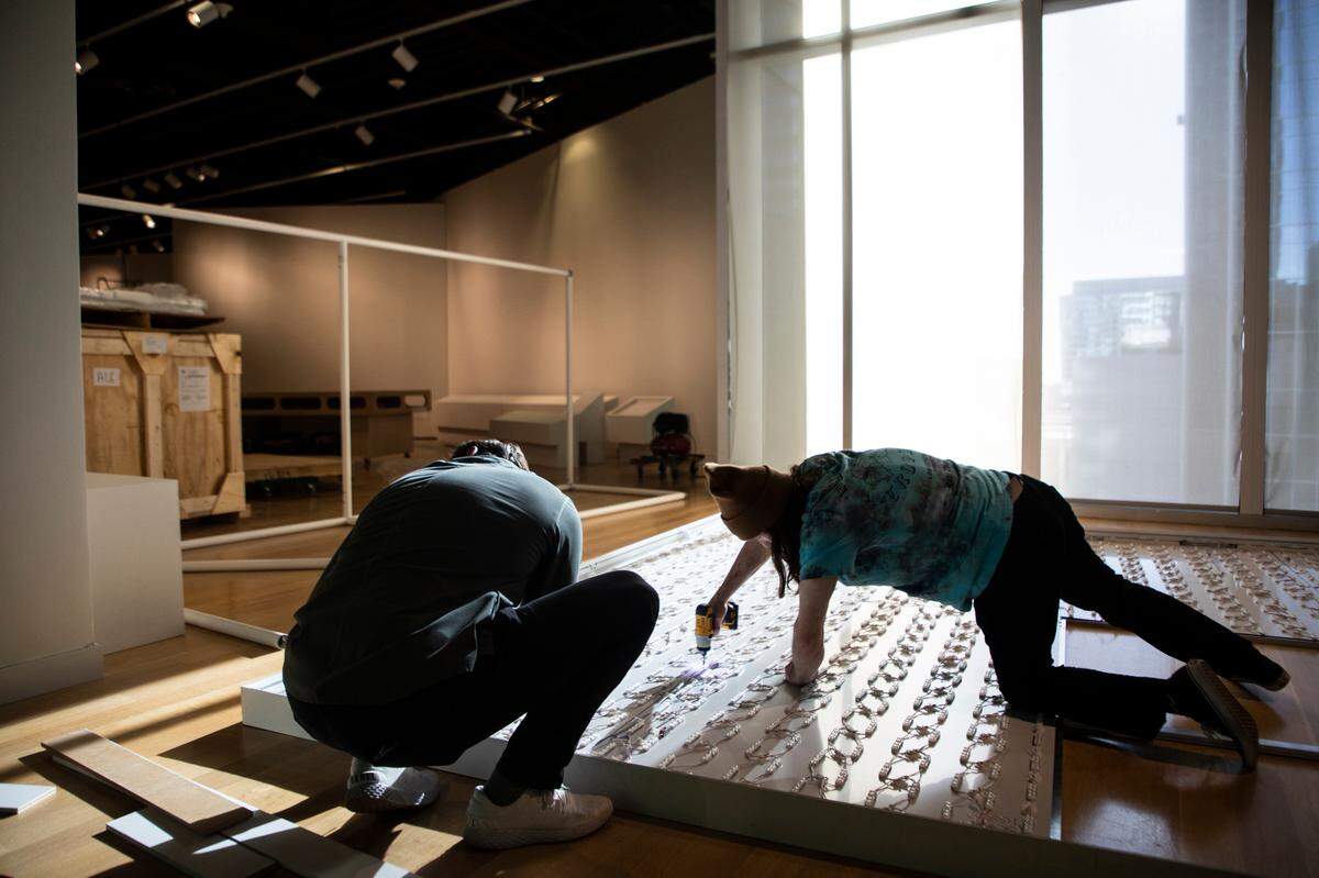 Zach Short, left, and Isaiah Smith, right, screw a light board onto a frame that will display a photo of Pablo Picasso at Mint Museum Uptown in Charlotte for the upcoming “Picasso Landscapes: Out of Bounds exhibition.