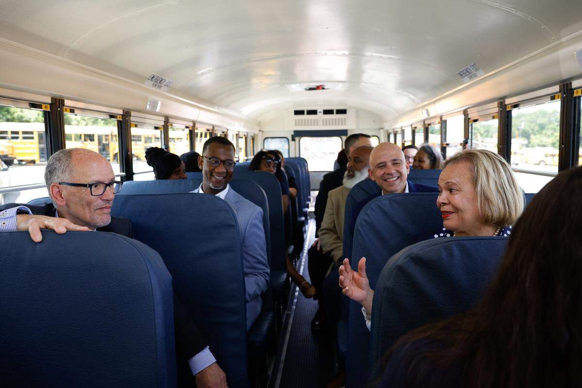 Tom Perez, senior advisor to President Joe Biden and White House director of intergovernmental affairs, left, listens to Mayor Vi Lyles, right, as they take a ride on an electric school bus during an event in Charlotte.