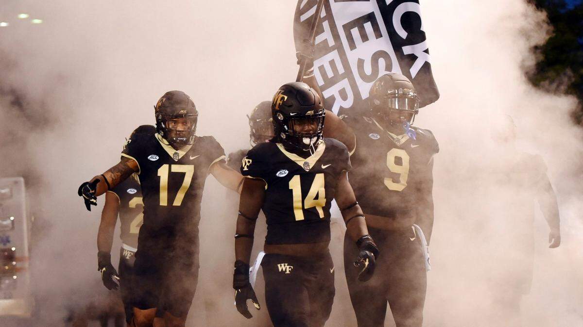Wake Forest defensive end Carlos “Boogie” Basham carries a Black Lives Matter flag onto the field before the team’s NCAA college football game against Clemson, Saturday, Sept. 12, 2020, in Winston-Salem, N.C. (Walt Unks/The Winston-Salem Journal via AP)
