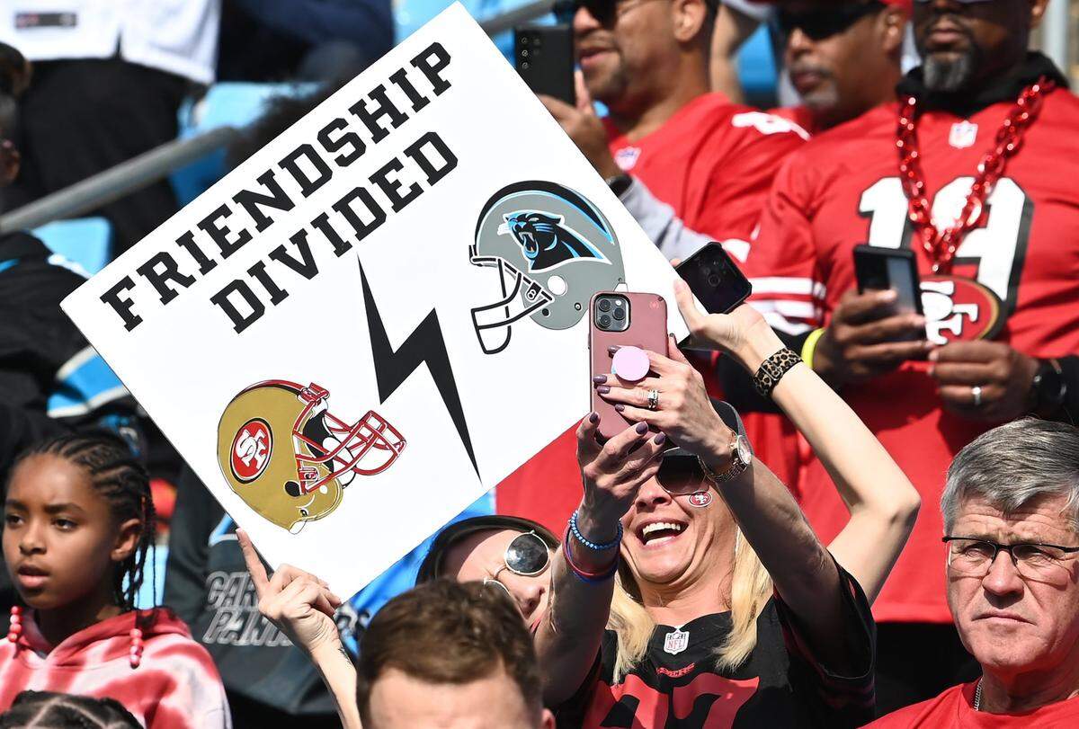 A San Francisco 49ers fan and Carolina Panthers fan smile as they take a selfie in the stands at Bank of America Stadium on Sunday, October 9, 2022.