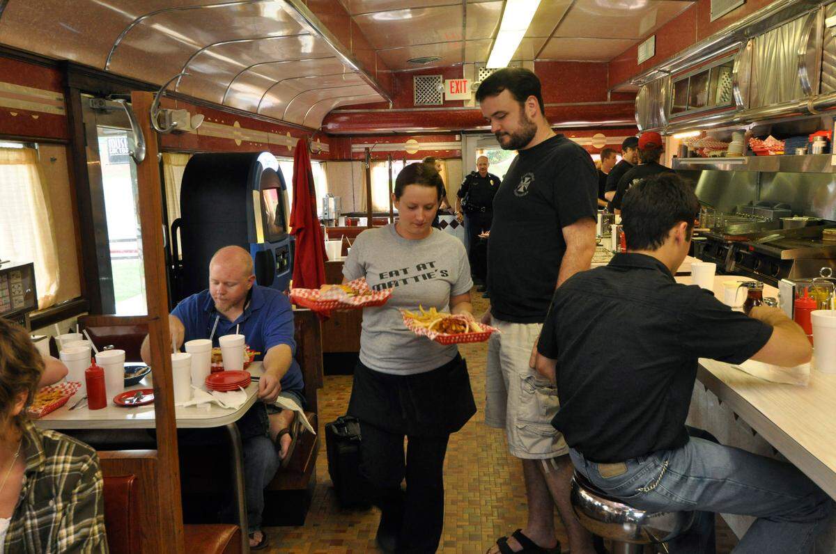 Waitress Rossi Trotter walks by as customer Pierce Cook glances at the food during opening night on August 6, 2010, at Mattie’s Grill.