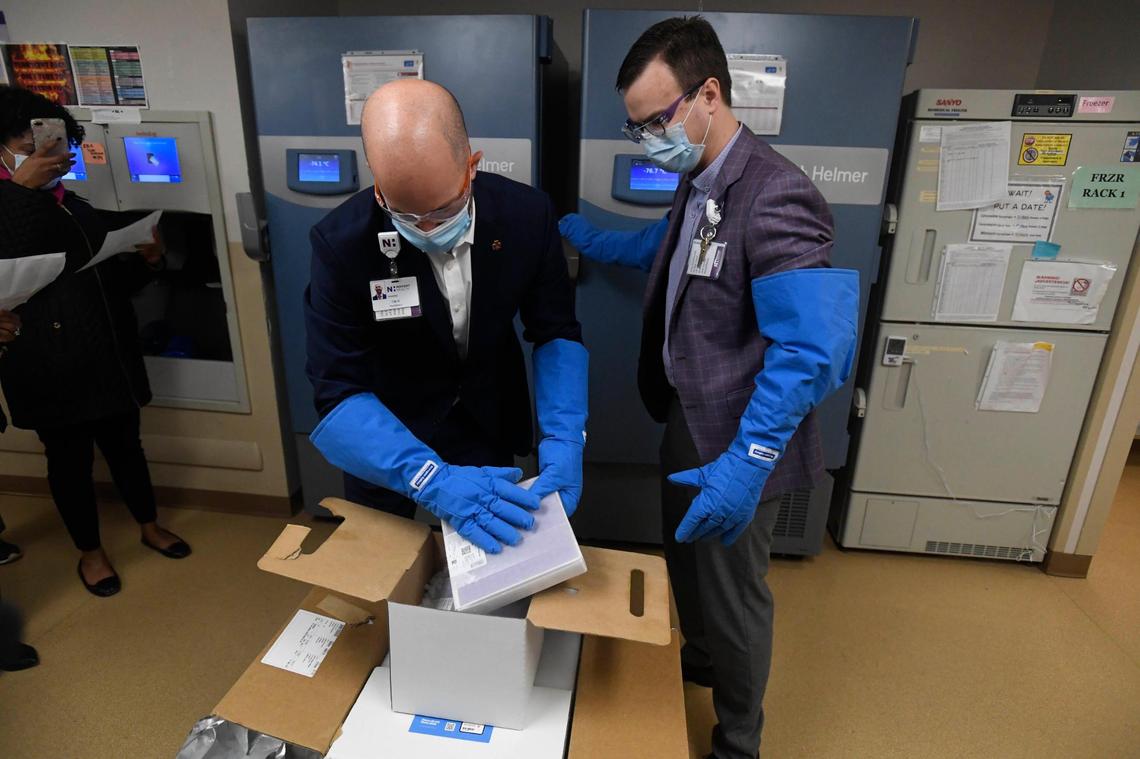 Novant Health’s Tim Randolph, left, Director of Pharmacy for the Greater Charlotte Market, and Brad Petersen, right, Pharmacy Operations Manager, unpack the first containers of COVID vaccine at Novant Health Presbyterian Medical Center after it was delivered on Thursday, December 17, 2020.