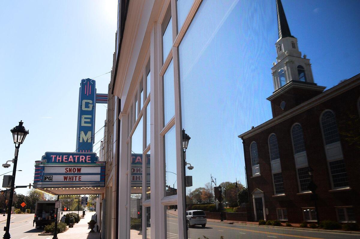 The First Baptist Church of Kannapolis is reflected in windows near the still-operating, historic Gem Theatre on Thursday.