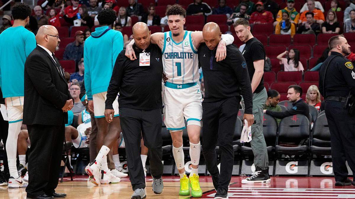 Charlotte Hornets’ LaMelo Ball (1) is helped off the court after being injured during the second half of an NBA basketball game against the Houston Rockets Wednesday, Jan. 18, 2023, in Houston. The Hornets won 122-117. (AP Photo/David J. Phillip)