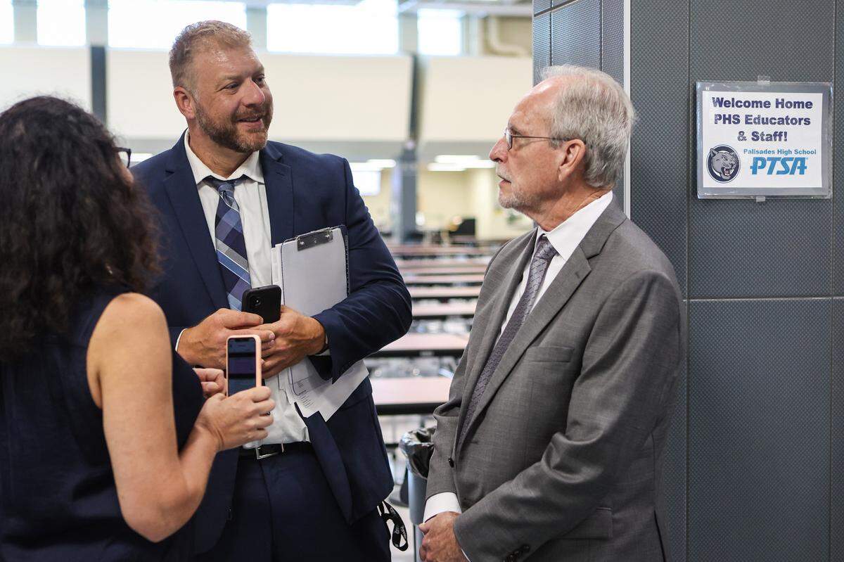 Principal Erik Olejarczyk, center, speaks with Interim Superintendent Hugh Hattabaugh watches students walk to class during the first day of school at Palisades High School, a brand new CMS campus, on Monday, August 29, 2022 in Charlotte, NC.