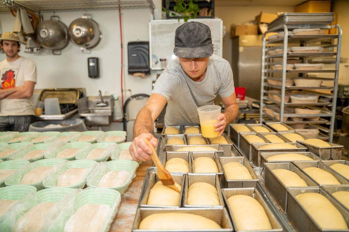 Verdant Bread employee Robert Von Hedrich butters the loaves.
