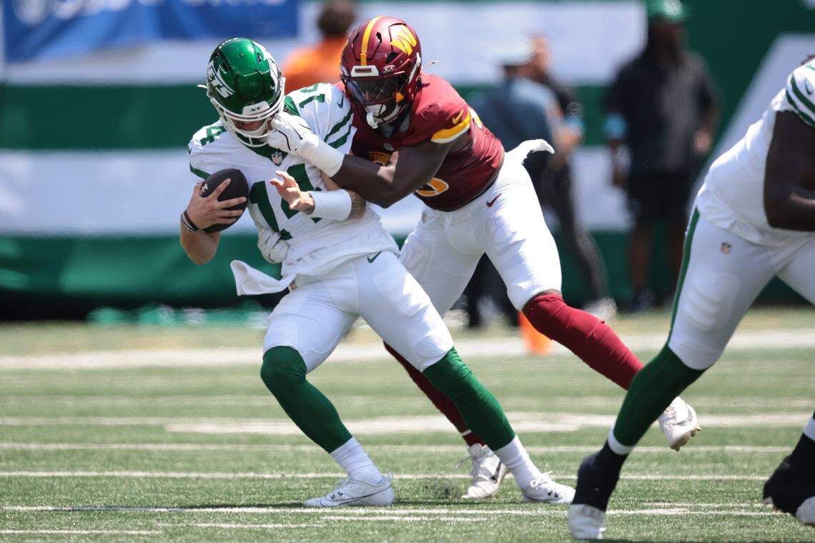 Aug 10, 2024; East Rutherford, New Jersey, USA; New York Jets quarterback Andrew Peasley (14) is sacked by Washington Commanders defensive end KJ Henry (55) during the first half at MetLife Stadium. Mandatory Credit: Vincent Carchietta-USA TODAY Sports