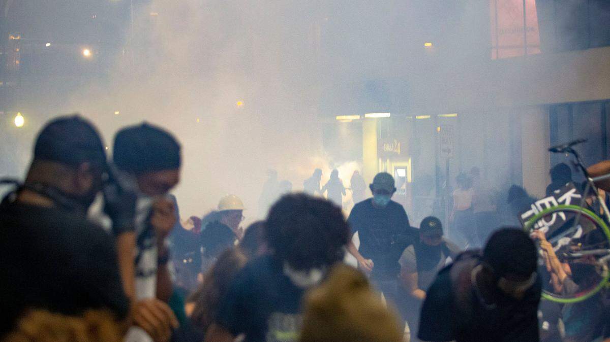 Protesters scramble on 4th Street as police fire chemical agents on either side of the protesters in uptown Charlotte, NC on Tuesday, June 2, 2020.