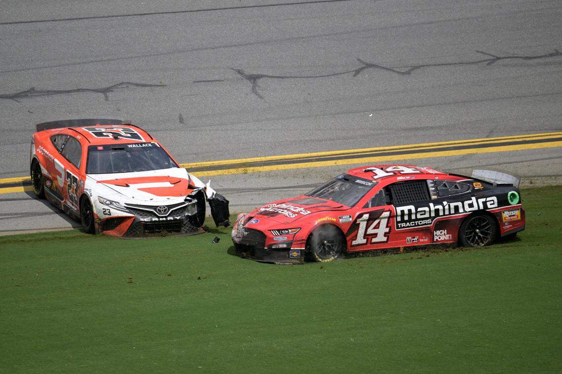 Chase Briscoe (14) and Bubba Wallace (23) slide along the front stretch after getting involved in a multi-car wreck during a NASCAR Cup Series auto race at Daytona International Speedway, Sunday, Aug. 28, 2022, in Daytona Beach, Fla. (AP Photo/Phelan M. Ebenhack)