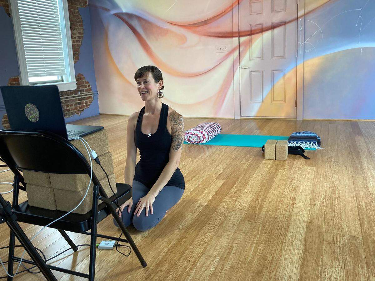 Carrie Wren of NoDa Yoga teaches virtual classes via Zoom with the studio’s new mural by Sydney Duarte and Nick Napoletano in the background.