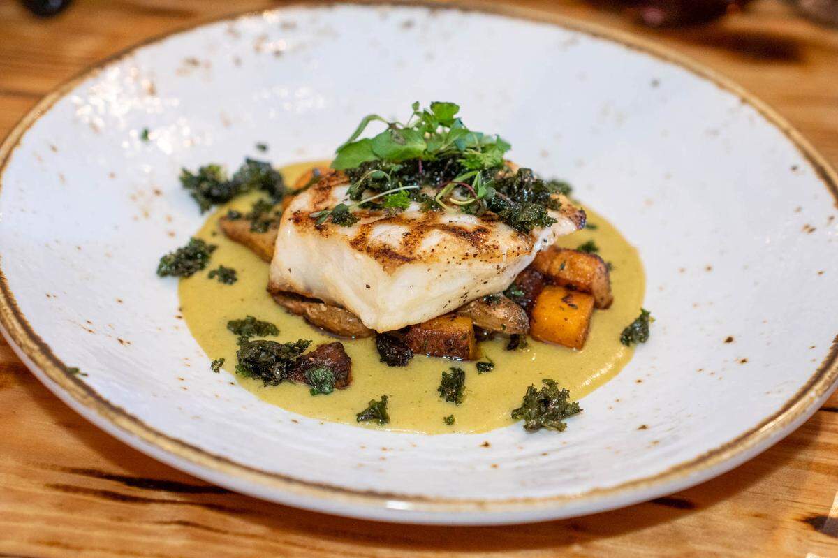 Barrel & Fork’s wild caught sea bass with poblano crema ancho chile spiced fingerlings and butternut squash with crispy kale.