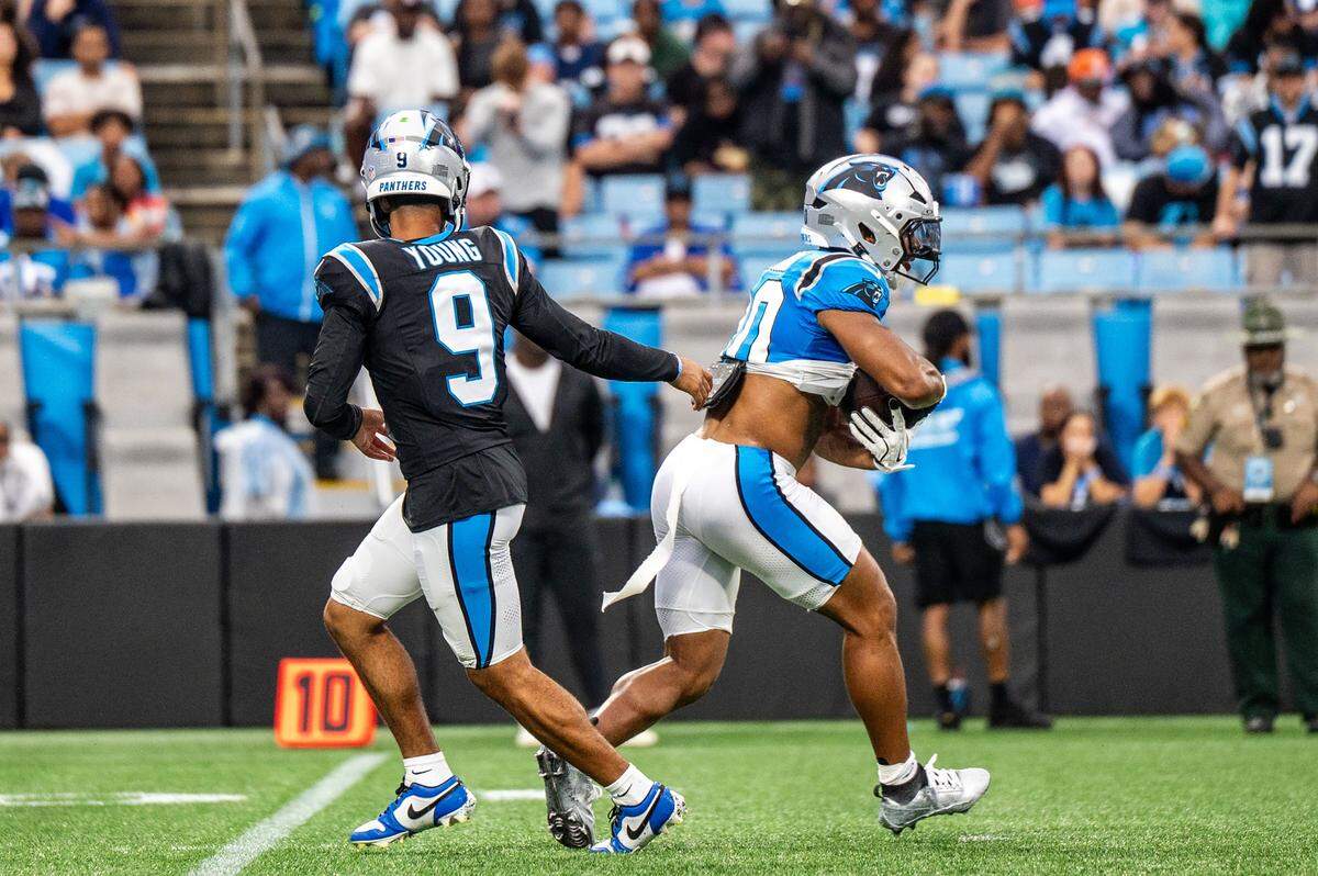 Carolina Panthers quarterback Bryce Young hands the football off to running back Chuba Hubbard during the Carolina Panthers' fan fest open practice at Bank of America Stadium in Charlotte on Aug. 2, 2025.
