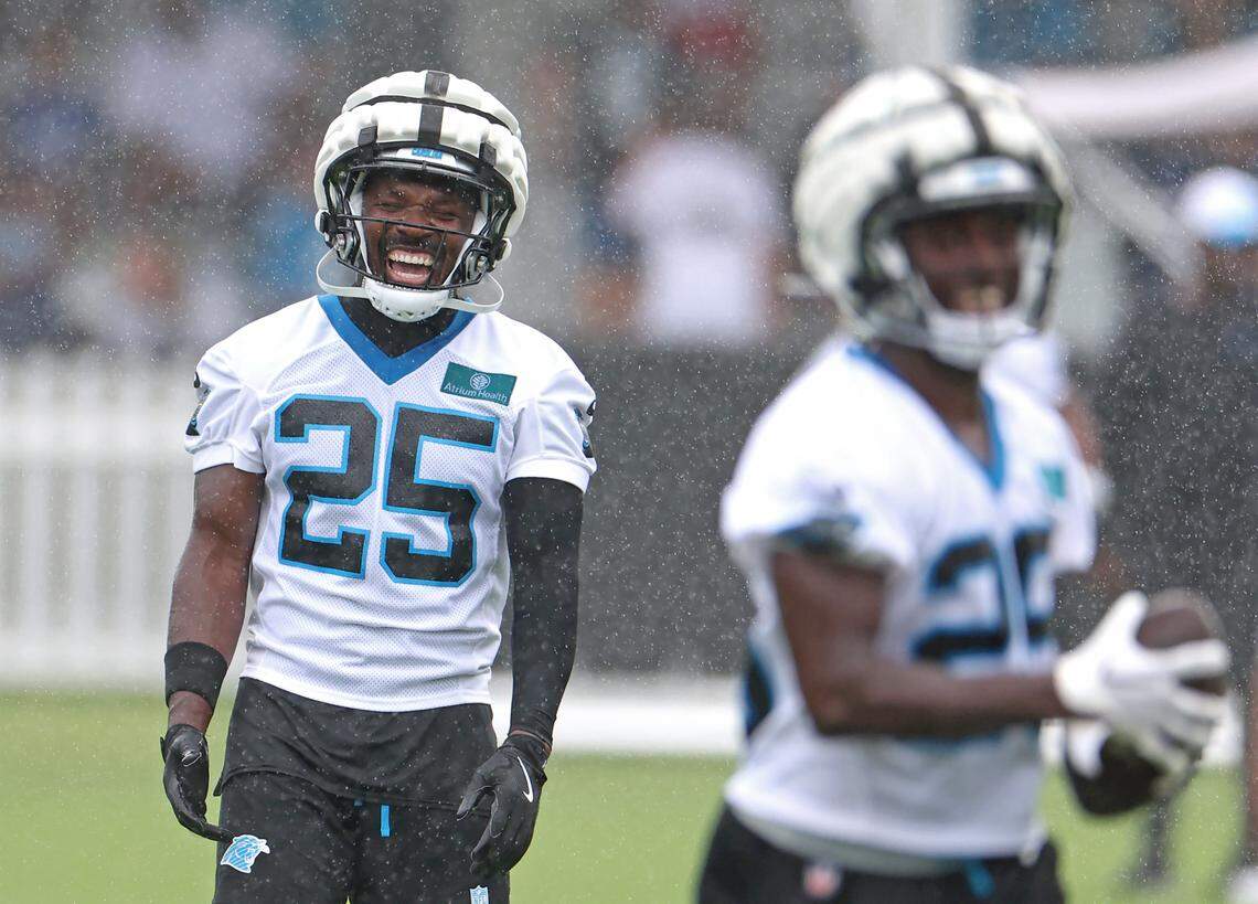Carolina Panthers safety Xavier Woods, left, does not let the falling rain dampen his mood during practice on Thursday, July 25, 2024.