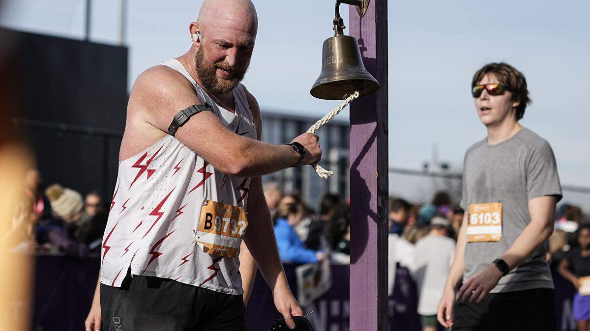 A participant rings a bell after competing in the Novant Health Charlotte Marathon Saturday, Nov. 15, 2025, in Charlotte, N.C.
