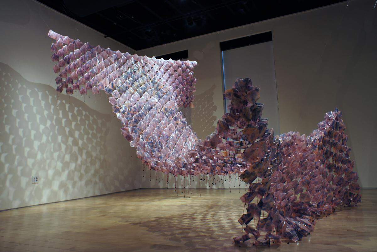 This work from Jan-Ru Wan is part of “The Noise We Make” exhibition opening May 1 at The Mint Museum Uptown. Wan incorporates found objects and gives them new purpose as a part of her sculptural installations. This piece was made from printed and folded plastic, thread, and rusted metal bells.