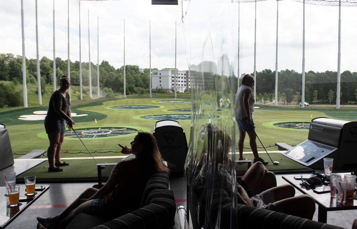 Original: Golfers in different groups are partitioned by plastic sheets in between golfing bays after Topgolf reopened during the coronavirus pandemic in Charlotte, N.C., on Monday, August 3, 2020. Topgolf management reports that all bays and their equipment are sanitized after use.