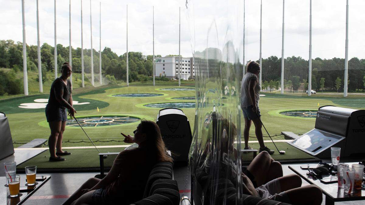 Original: Golfers in different groups are partitioned by plastic sheets in between golfing bays after Topgolf reopened during the coronavirus pandemic in Charlotte, N.C., on Monday, August 3, 2020. Topgolf management reports that all bays and their equipment are sanitized after use.
