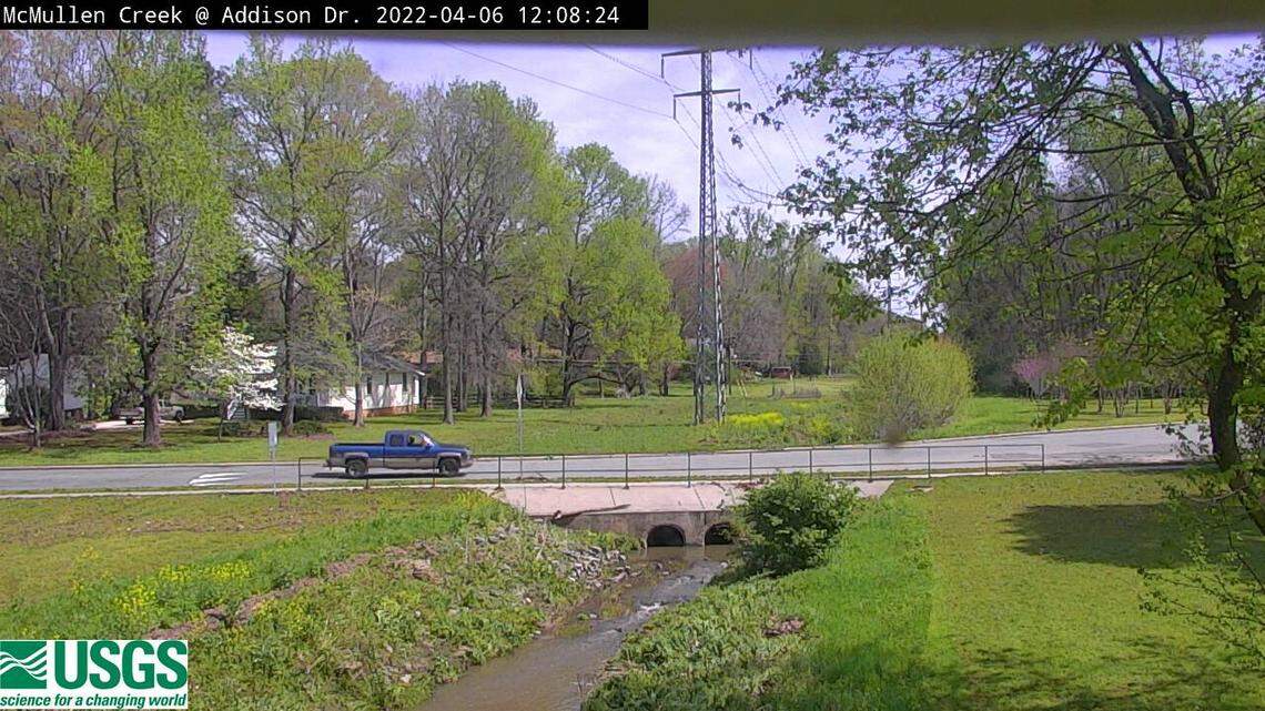 This image from a US Geological Survey webcam shows McMullen Creek down to a normal level at Addison Drive in Charlotte, NC, on Wednesday, April 6, 2022. A day earlier, heavy rains forced the creek to spill onto the roadway.