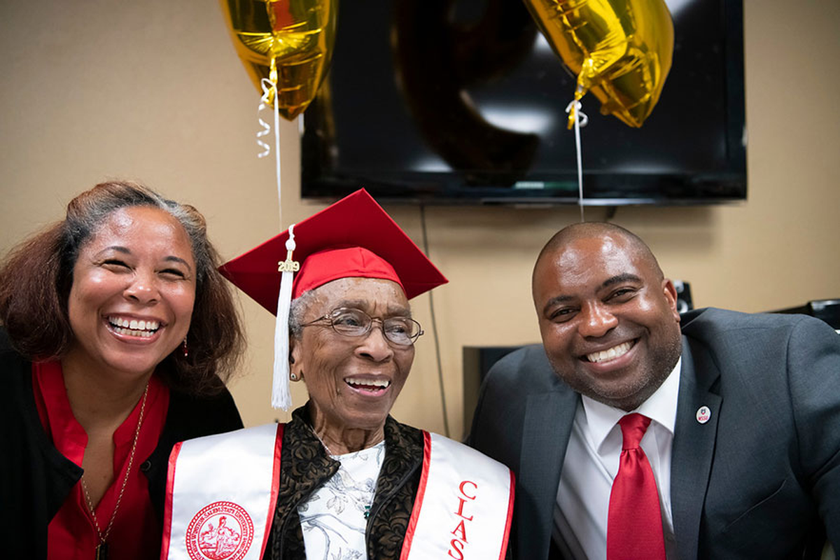 In May 2019 at Winston-Salem State University, Shannon Mathews , left, interim associate dean of the College of Arts, Sciences, Business and Education and College Dean Darryl Scriven shared a moment with Elizabeth Barker Johnson, Class of ’49. Johnson was the first female to enroll at what was then Winston-Salem Teachers College on the GI Bill. She earned a degree in education in August 1949. Johnson, 99 at the time, had not been able to march when she graduated in 1949 but did so in 2019.