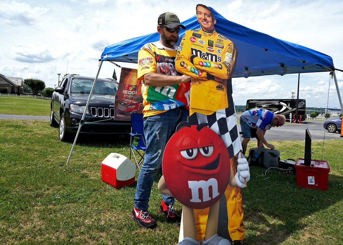 NASCAR fan Larry Bickley of Charlotte, NC ties a cutout of driver Kyle Busch to his and friend David Magnussen's tent outside of Charlotte Motor Speedway on Sunday, May 24, 2020. Despite not being allowed into the Coca-Cola 600 due to COVID-19 regulations, Bickley and Magnussen showed up in hopes of hearing the cars and smelling the rubber. The tent featured a flat screen tv, Sirius radio along with chairs and drinks.                           