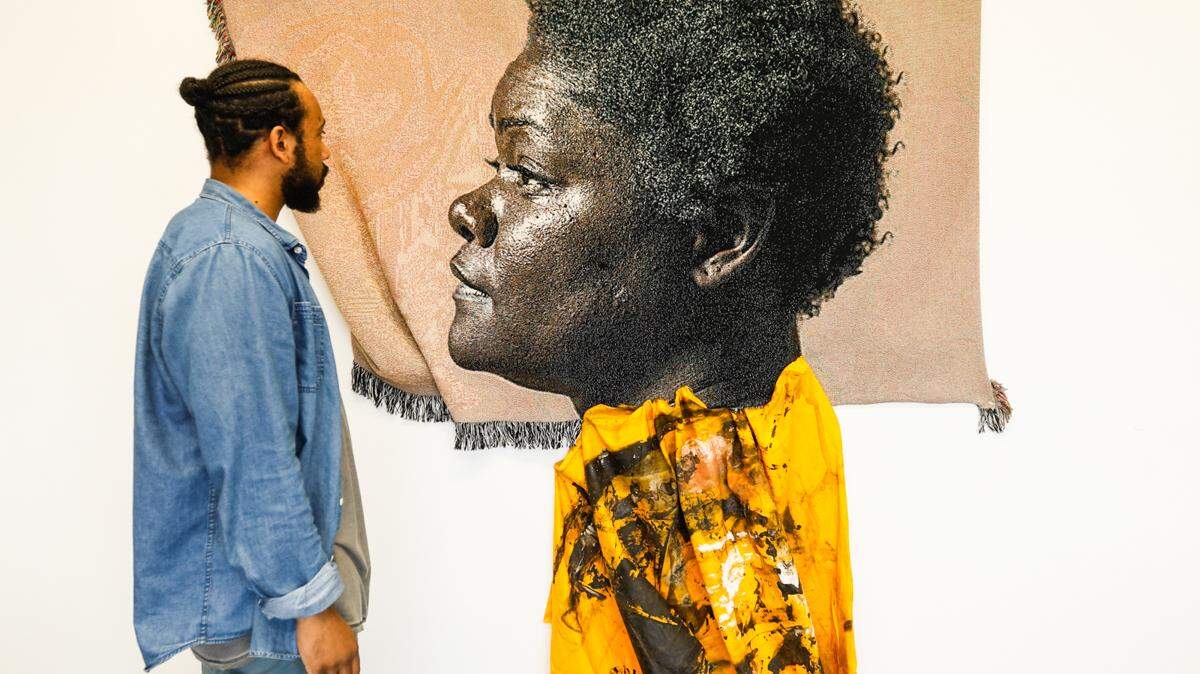 Artist Johannes Barfield of Winston-Salem views his piece titled “The Green House on Cornell Blvd.,” which focuses on his family and growing up African-American in the South. Barfield’s piece won the $10,000 Best in Show Award at “Coined in the South,” a juried exhibition on display at the Mint Museum Uptown.