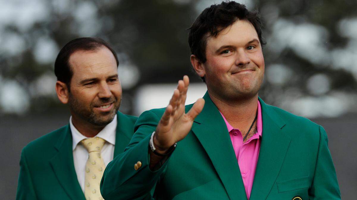 Former Masters champion Sergio Garcia, left, of Spain, watches as Patrick Reed waves to spectators after winning the Masters golf tournament Sunday, April 8, 2018, in Augusta, Ga. (AP Photo/David J. Phillip)