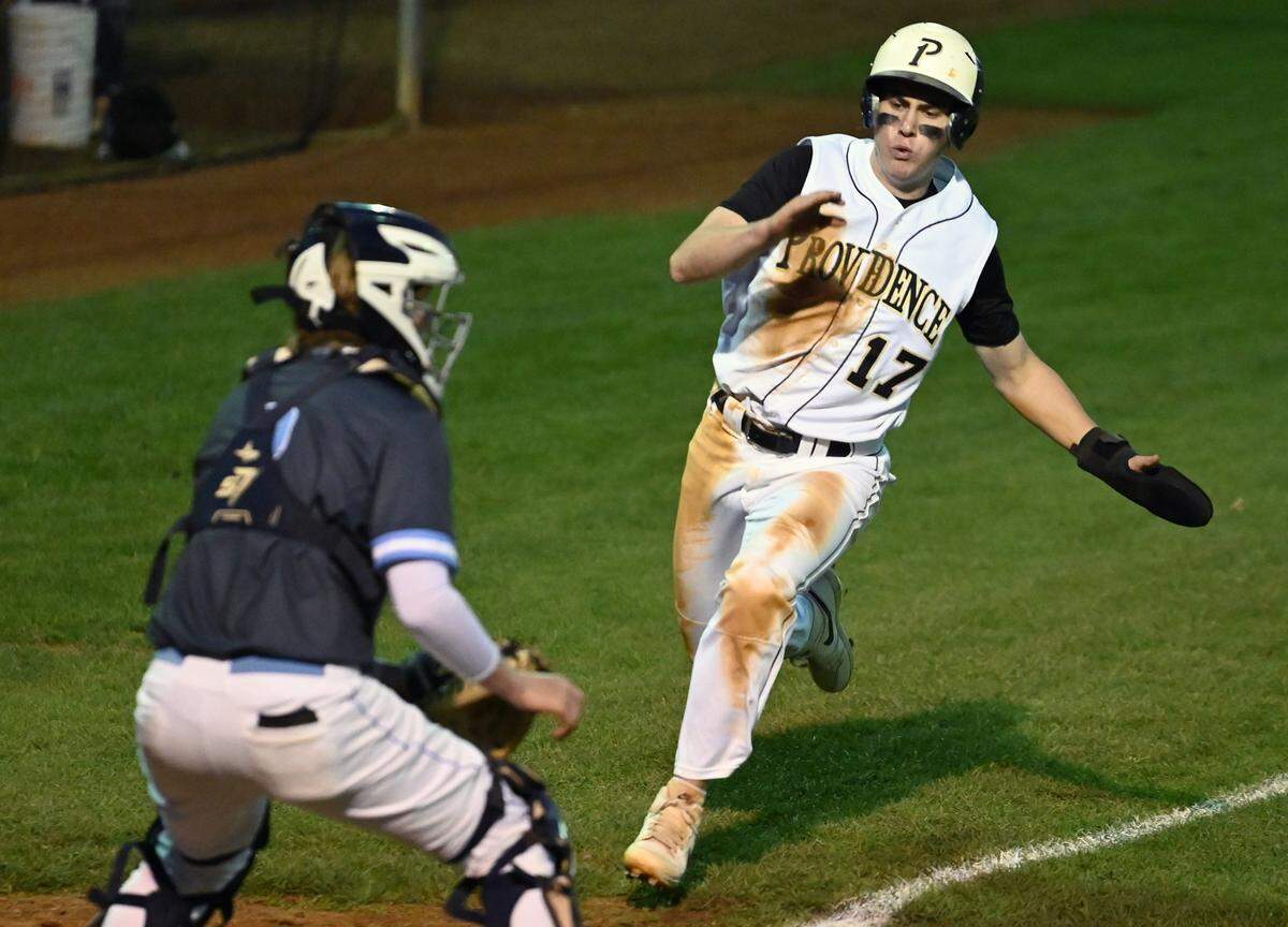Providence Panthers left fielder Seth Hartnett, right, prepares to slide into home plate for a run during action against Hopewell on Friday, April 12, 2024.