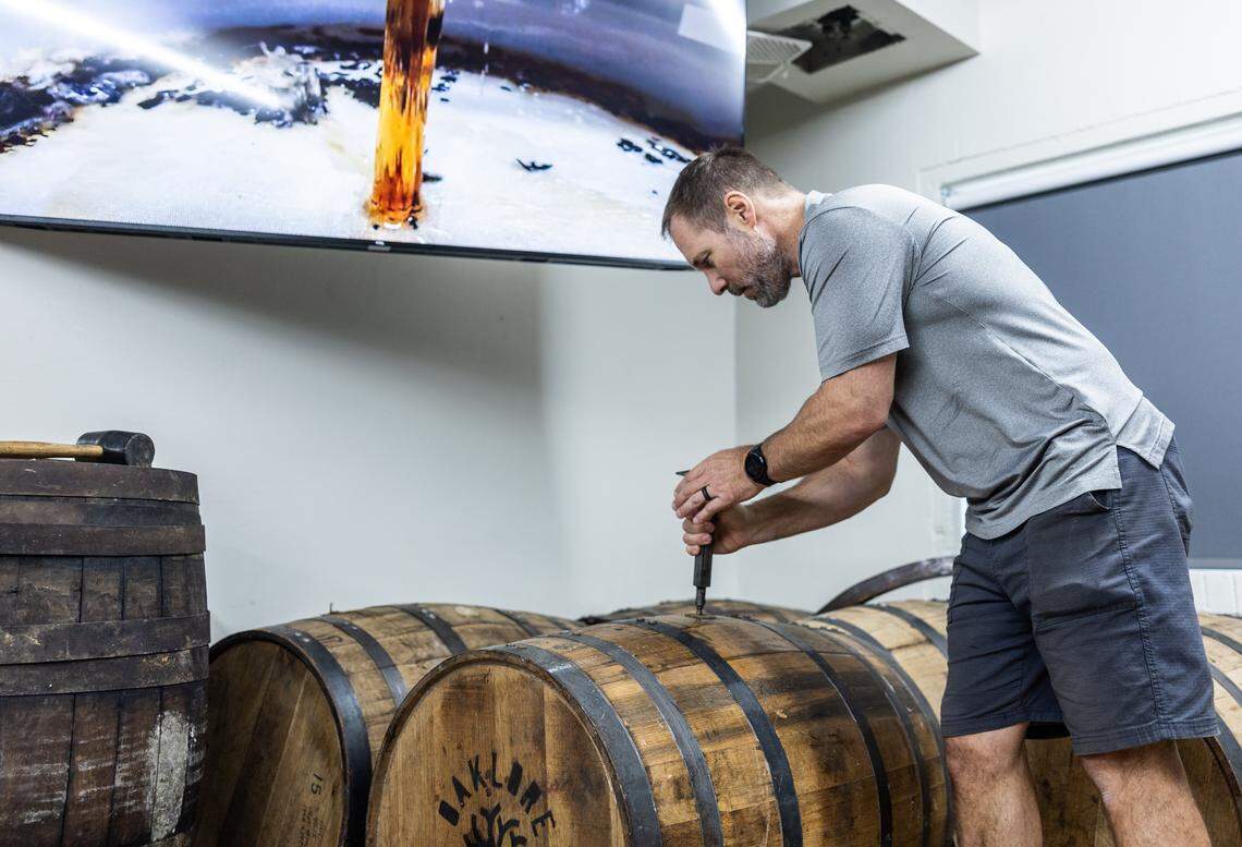 Tom Bogan gets a sample of a coffee liqueur out of a barrel  at Oaklore Distilling Co. in Matthews, N.C., on Tuesday, September 30, 2025.