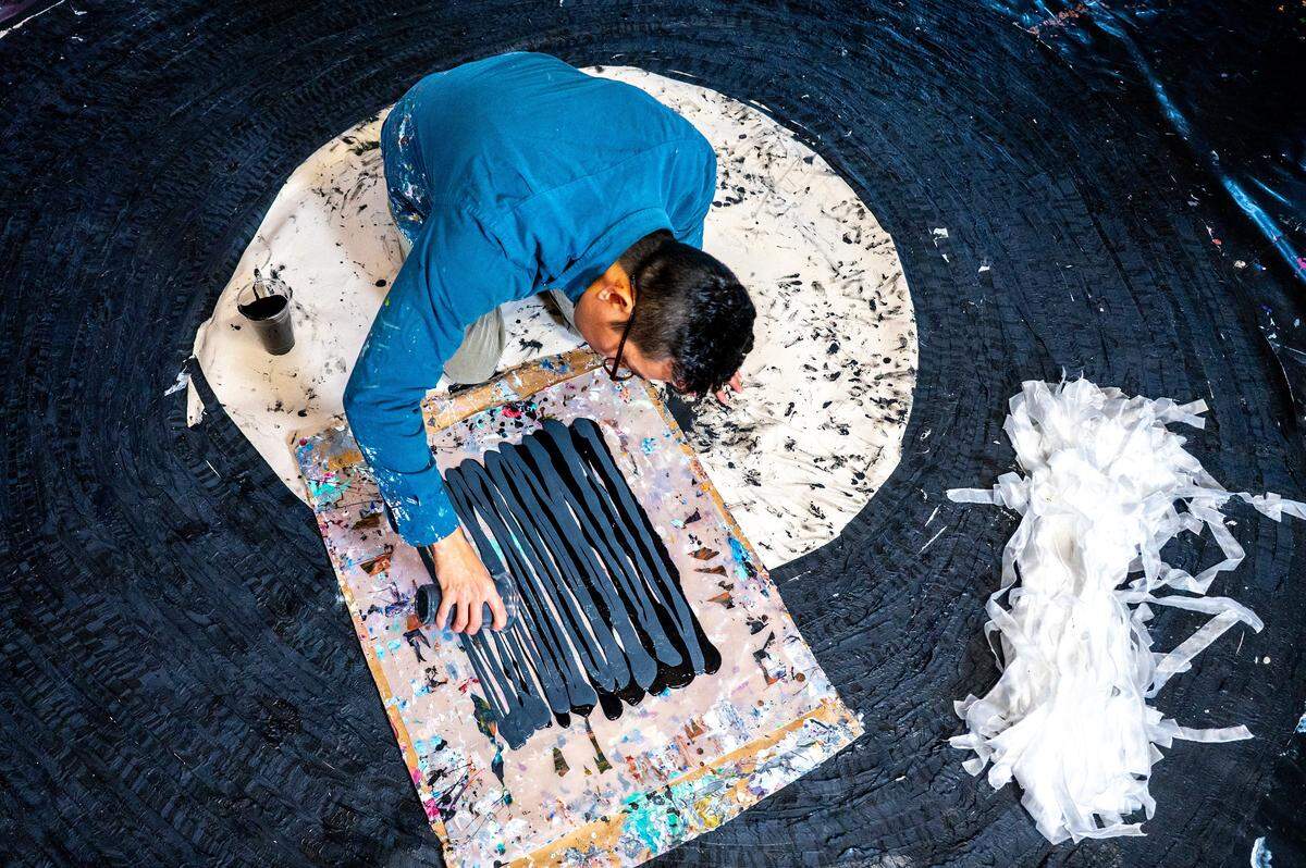 Kenny Nguyen, a Charlotte based artist, prepares a canvas of paint to dip strips of silk into in his Concord studio in Concord, NC, Tuesday August 1, 2025.
