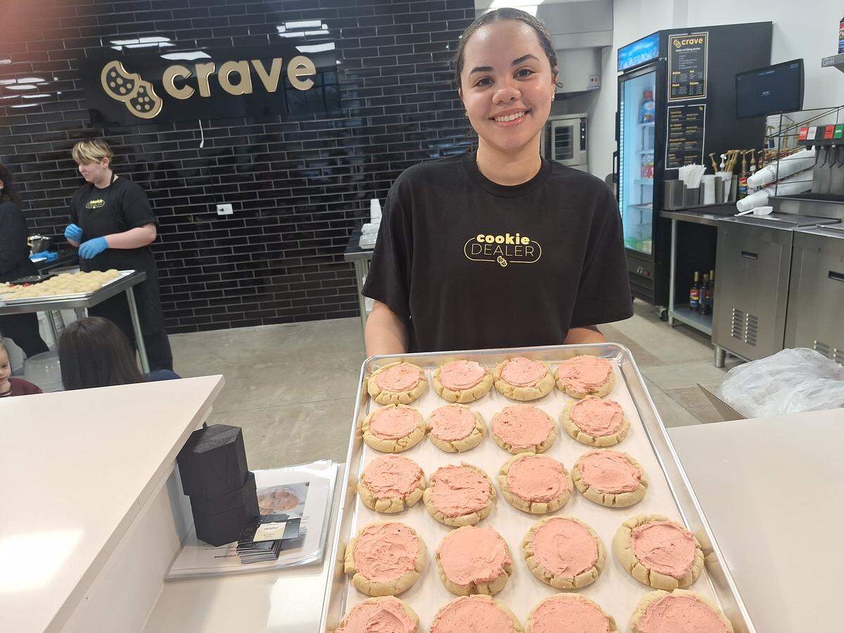 Teja Turner, a baker at Crave Cookies in Mooresville, holds a fresh-out-of-the oven tray of Sweetheart Sugar cookies on Wednesday, Feb. 18, 2026.