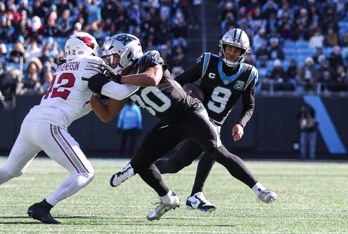 Panthers quarterback Bryce Young, right, runs around a block by Chuba Hubbard during the game against the Cardinals at Bank of America Stadium in Charlotte, NC on Sunday, December 22, 2024.