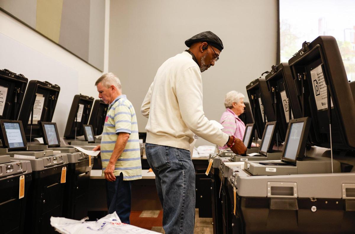 Volunteers feed ballots into ballot machines.