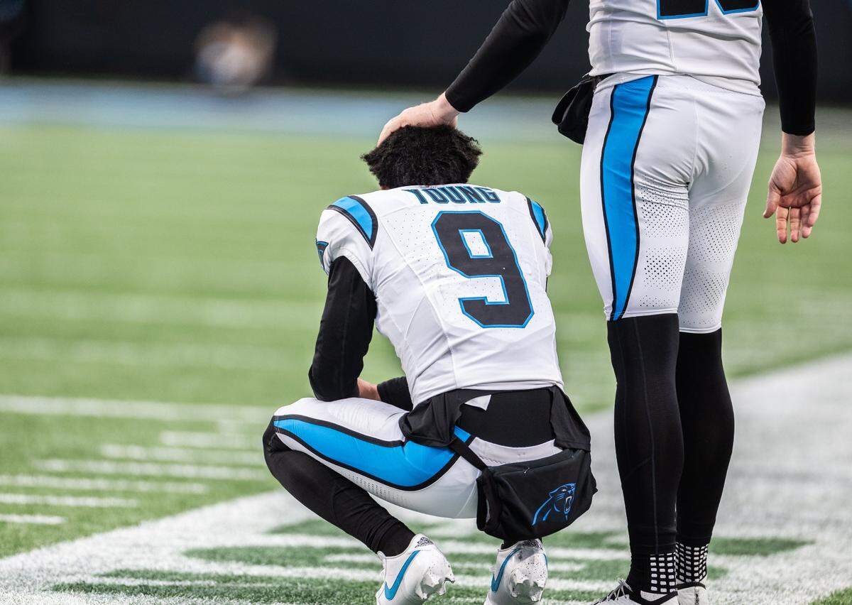 Carolina Panthers punter Johnny Hekker, right, pats Carolina Panthers quarterback Bryce Young on the head as he squats on the sideline at the Bank of America Stadium in Charlotte on Sunday, December 15, 2024.