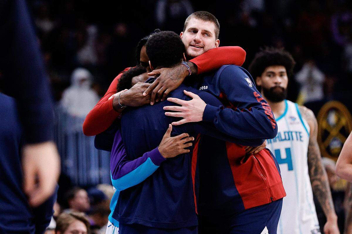 Denver Nuggets center Nikola Jokic (15) and guard Jamal Murray (27) and center DeAndre Jordan (6) hug Charlotte Hornets guard Ish Smith (14) after the game at Ball Arena.