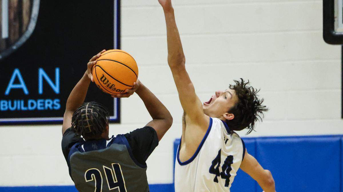 Hickory Ridge Ragin’ Bulls Travien Williams, left, shoots past a block by Lake Norman Wildcats Trent Steinour at Lake Norman High School in Mooresville, N.C., on Tuesday, February 6, 2024.