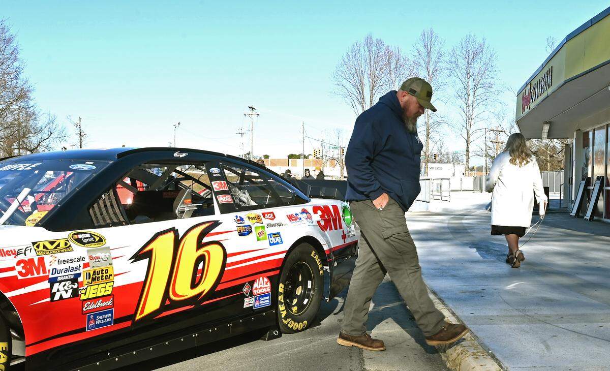 Michael Clinton of Cherryville walks beside one of former NASCAR driver Greg Biffle’s race cars parked outside Bojangles Coliseum on Friday in Charlotte. Three of Biffle’s old race cars were displayed outside prior to a service to remember the seven people killed in a plane crash on Dec. 18, 2025, in Statesville. Biffle, his wife and his two children all lost their lives in the crash.