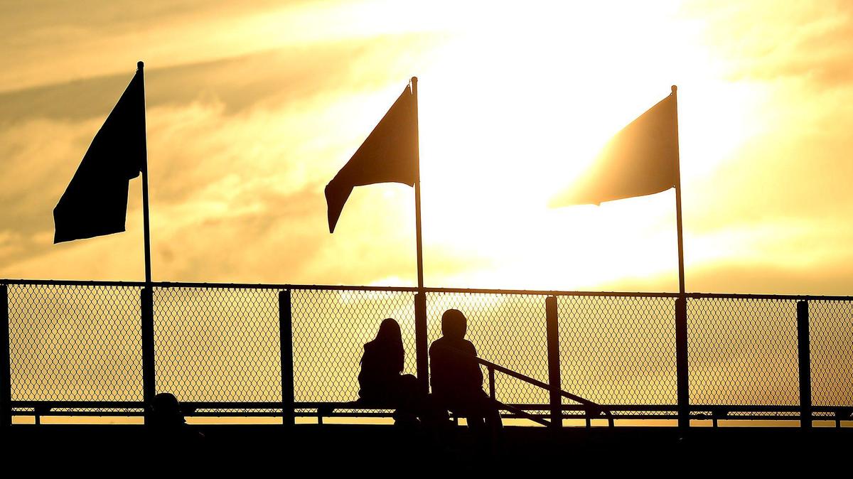 Fans at Hickory Ridge High School are silhouetted by the setting sun prior to the school’s football game against Myers Park on Friday, March 19. 2021.