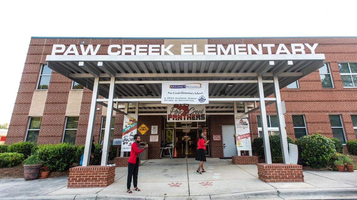 Counselor Sweet Flake, far left, and Principal Danielle Belton greet cars dropping off children during the first day of school at Paw Creek Elementary School on Aug.25, 2021 in Charlotte.