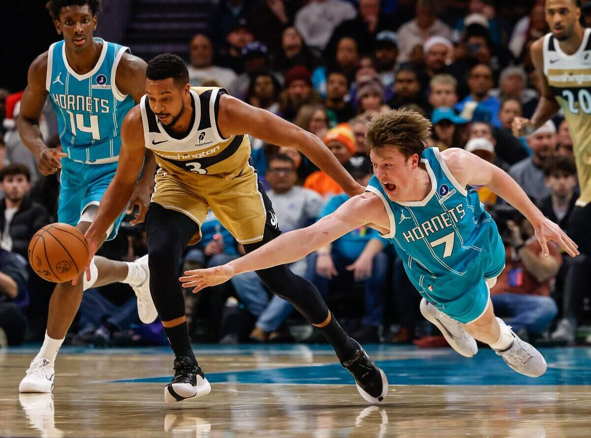 Hornets forward Kon Knueppel catches air as he extends his whole body to go after the ball as guard CJ McCollum dribbles away during the game at Spectrum Center in Charlotte on Tuesday, December 23, 2025.