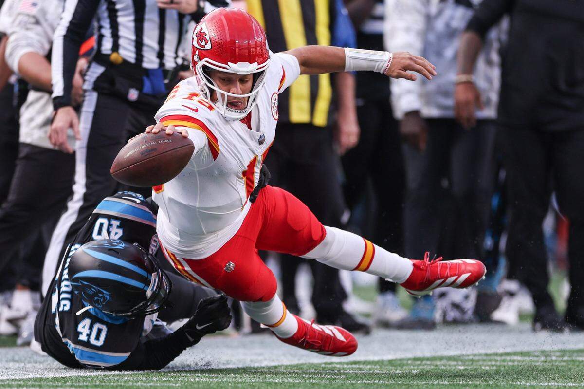 Chiefs quarterback Patrick Mahomes extends to keep the ball inbounds as he is tackled by Panthers outside linebacker Charles Harris during the game at Bank of America Stadium in Charlotte, NC on Sunday, November 24, 2024.