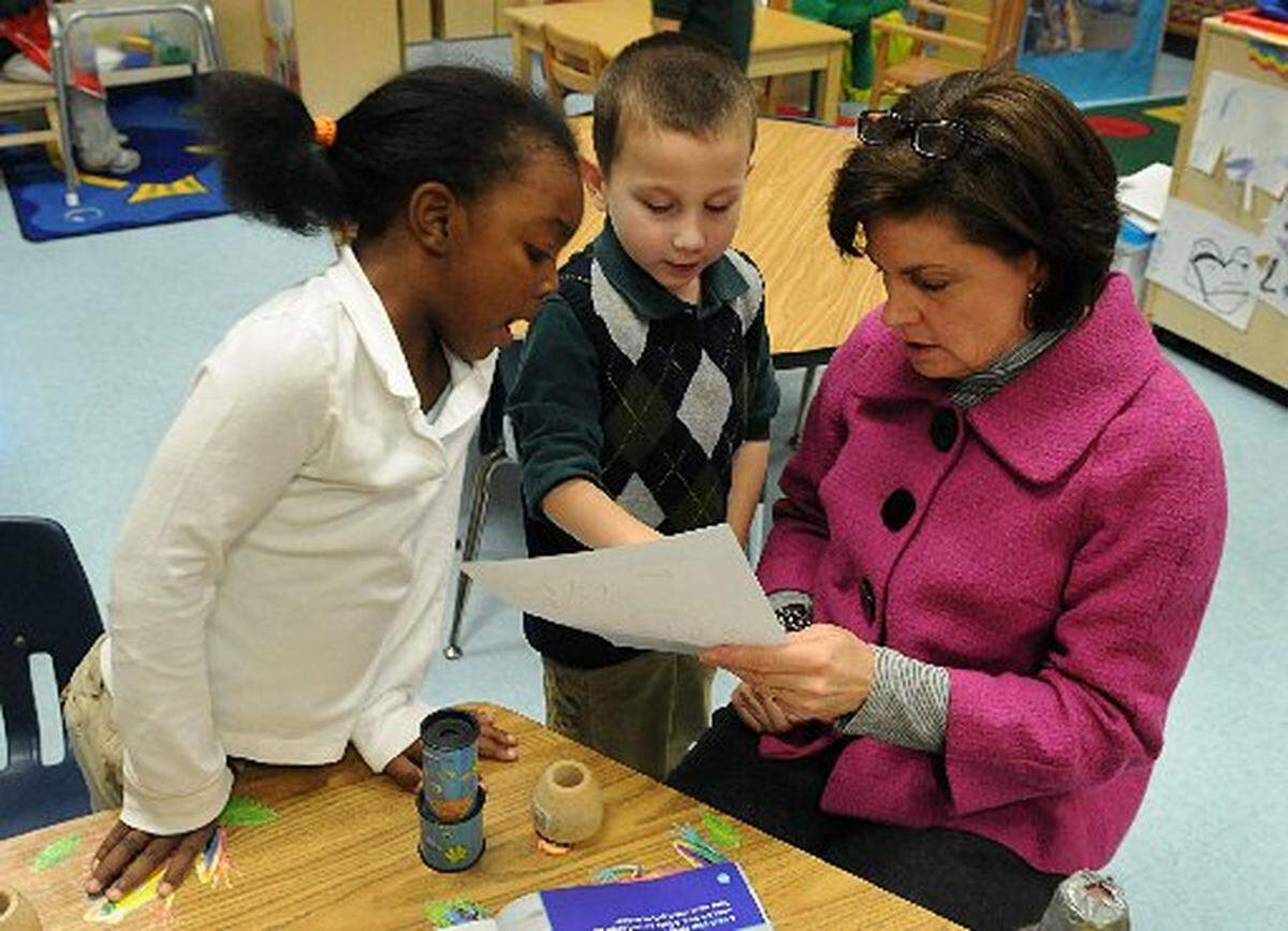 CMS and Mecklenburg County county leaders hope to boost enrollment and make it easier for parents to enroll their children in preschool. In this 2011 photo, Taleyna Craig (left), watches as fellow Winding Springs Elementary preschool student Francisco Rothenberger shows off his art work to their teacher, Phillis Robertson.