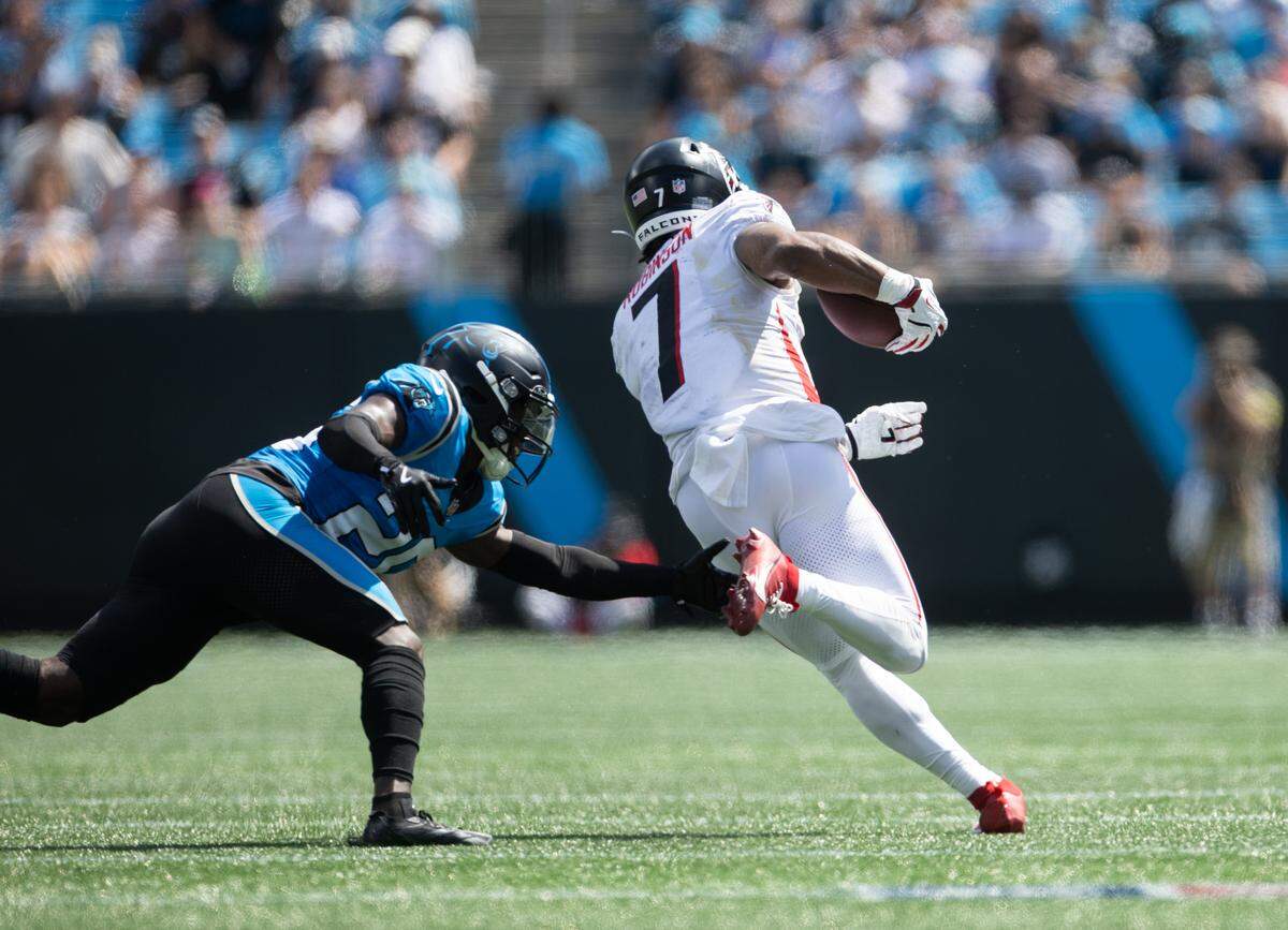 Carolina Panthers cornerback Chau Smith-Wade, left, reaches for Atlanta Falcons running back Bijan Robinson at the Bank of America Stadium in Charlotte on Sunday, September 21, 2025.