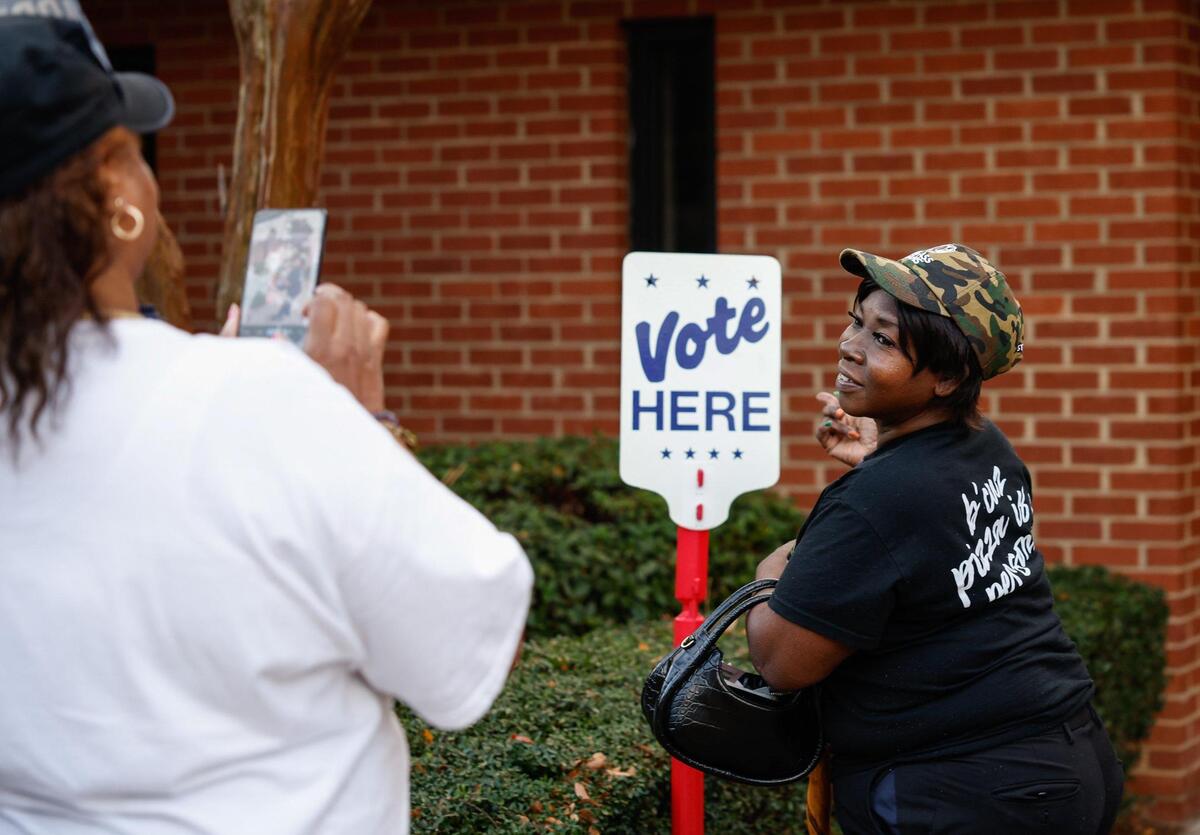 After voting, Glinda Blackwell poses for a photo next to the “Vote Here” sign at Ebenezer Baptist Church on election day in Charlotte, NC on Tuesday, November 5, 2024.