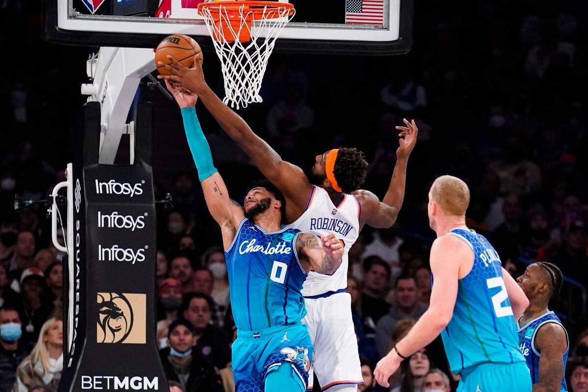 Charlotte Hornets forward Miles Bridges (0) blocks a shot by New York Knicks center Mitchell Robinson, center right, during the first half of an NBA basketball game, Monday, Jan. 17, 2022, in New York. (AP Photo/John Minchillo)