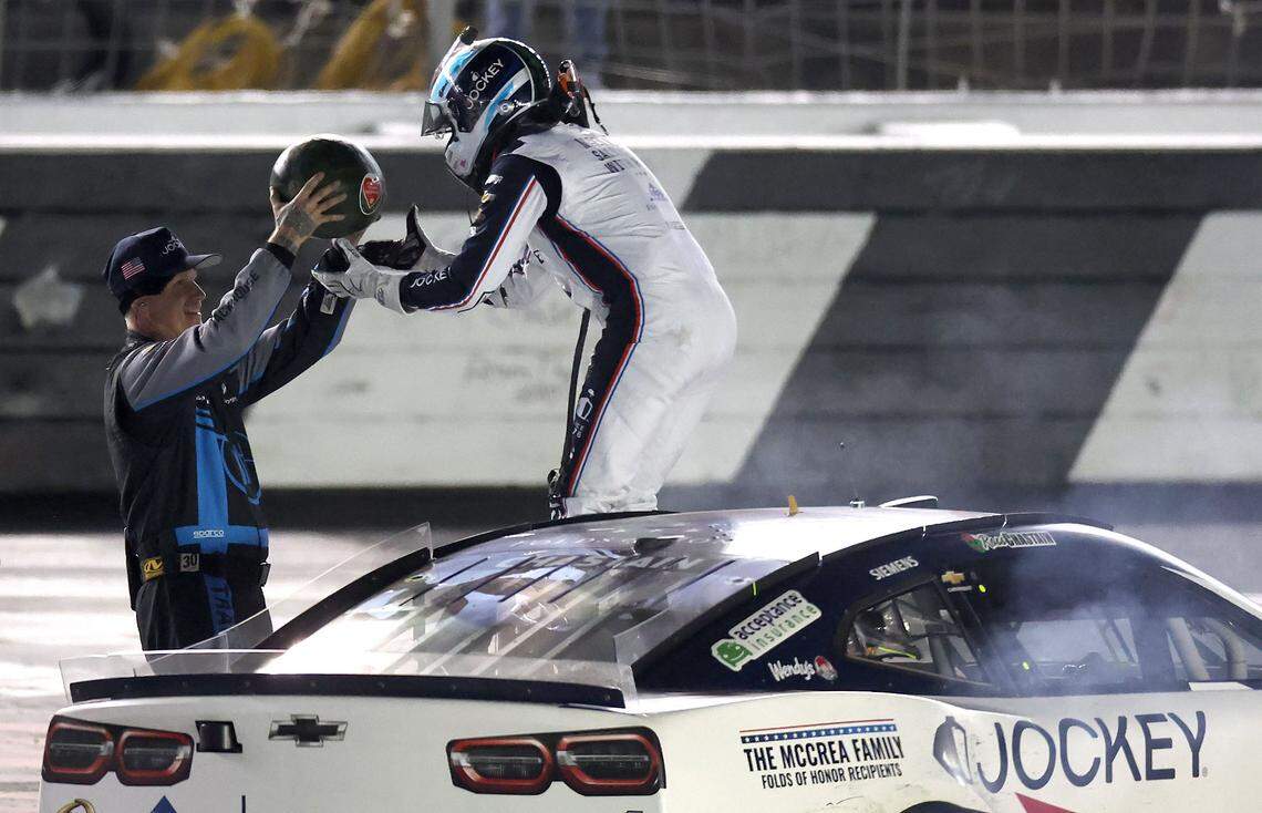 NASCAR Cup Series driver Ross Chastain, right, is handed a watermelon to smash on the frontstretch of Charlotte Motor Speedway after winning Sunday’s Coca-Cola 600 in Concord.