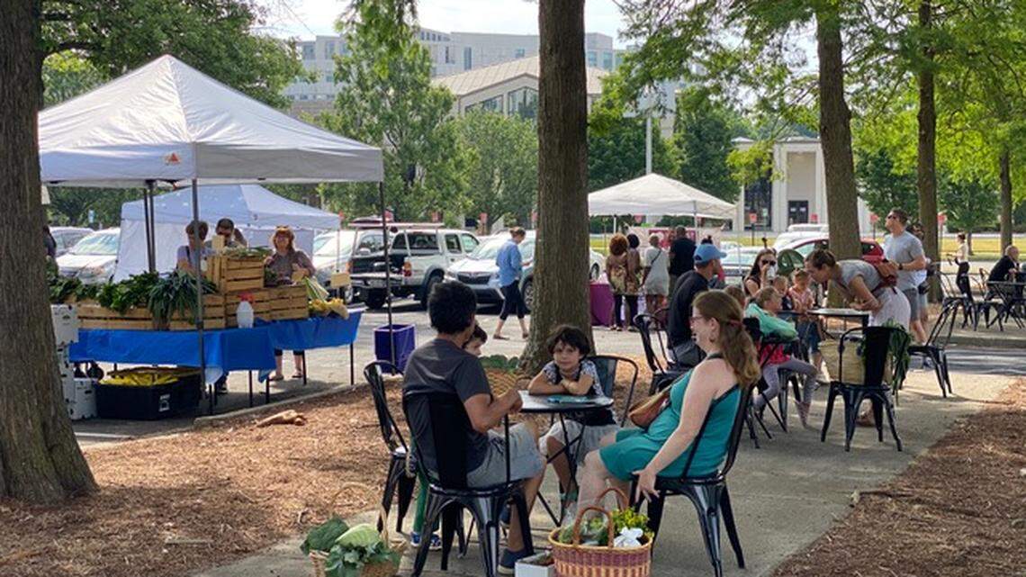 Patrons cool off in the shade after shopping for produce at the Uptown Farmers Market.